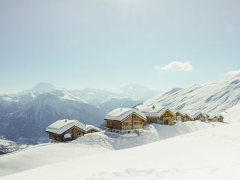 Houses on snow covered mountains against sky