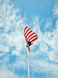 Low angle view of american flag waving against blue sky