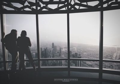 Rear view of man and woman looking through window