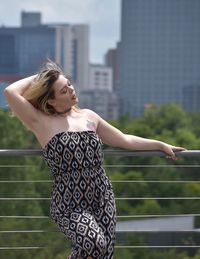 Young woman with arms raised standing against built structure