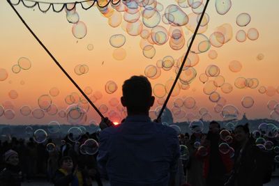 Rear view of two women standing against sky during sunset