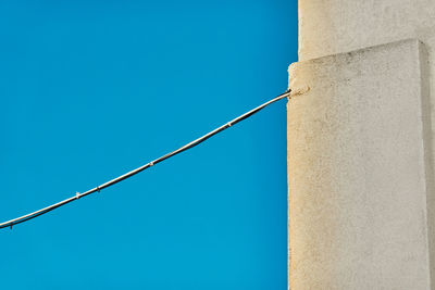 Low angle view of power lines against clear blue sky