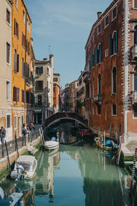 Boats moored on canal amidst buildings in city