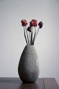 Close-up of red flower vase on table against wall