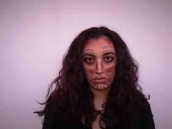 Portrait of young woman with face paint against wall