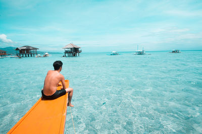 Rear view of man sitting in boat on sea