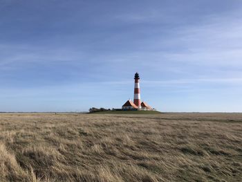 Lighthouse on field against sky