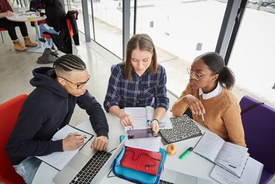 High angle view of students studying at table in university cafeteria