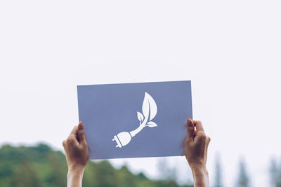 Close-up of hand holding paper against white wall