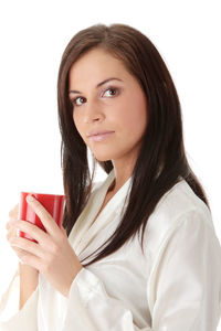 Portrait of a beautiful young woman drinking water against white background