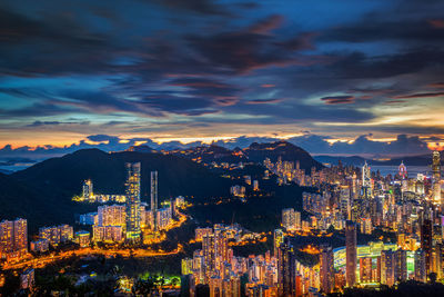 Illuminated cityscape against cloudy sky