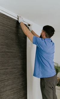 A young man removes the curtain rod.