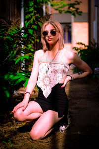 Young woman wearing sunglasses while standing against plants