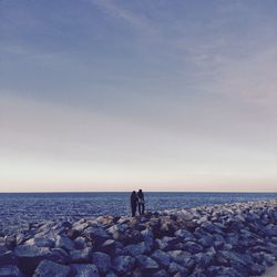 Rear view of women standing by sea against clear sky