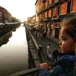 Rear view of boy on canal in city