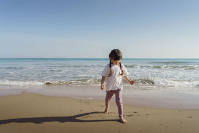 Rear view of girl walking at beach