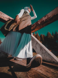 Rear view of woman standing on wood against sky