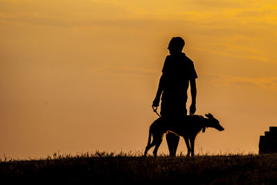 Silhouette men on field against sky during sunset