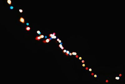 Low angle view of illuminated lights against black sky