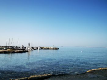 Sailboats in sea against clear blue sky