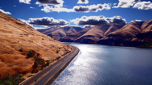 Scenic view of road by mountains against sky