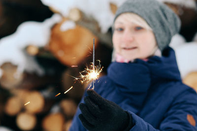 Portrait of woman holding sparkler in park