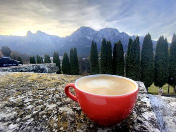 Cup of coffee on mountain against sky during winter