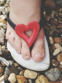 Close-up of hand holding heart shape on rock