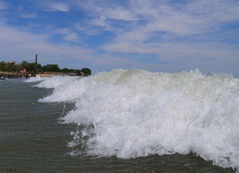 Waves splashing on shore against sky