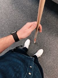 Low section of man holding stick while standing on carpet