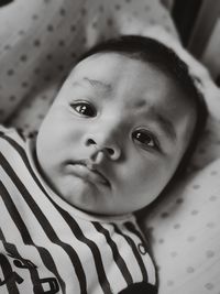 High angle portrait of cute baby girl lying on bed