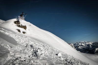 Man skiing on snowcapped mountain against sky