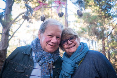 Portrait of senior couple smiling while standing against trees in forest