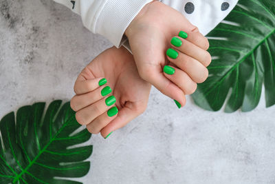 Manicured female hands with stylish green nails. trendy modern design manicure. gel nails. skin care