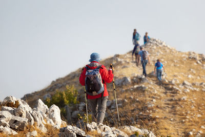 Rear view of people walking on mountain against clear sky