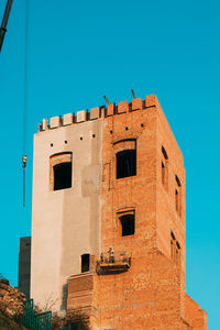 Low angle view of old building against clear blue sky