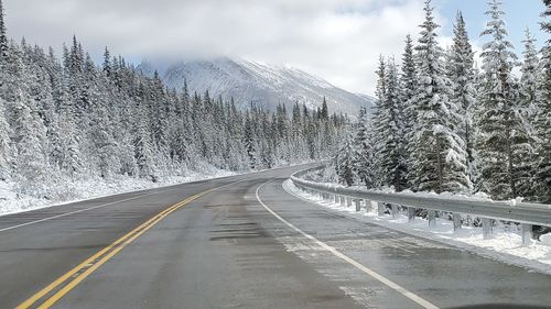 Road by snow covered mountain against sky