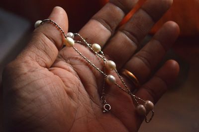 Close-up of hand holding bead necklace