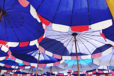 Low angle view of umbrellas against blue sky