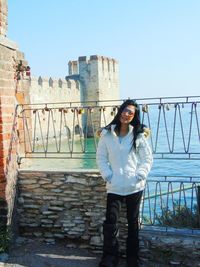 Portrait of smiling young woman standing against built structure