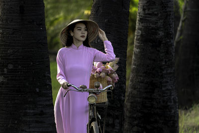 Woman standing by tree trunk in forest