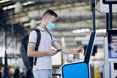 Man using self service check-in. passenger scanning ticket on smart phone at airport terminal.