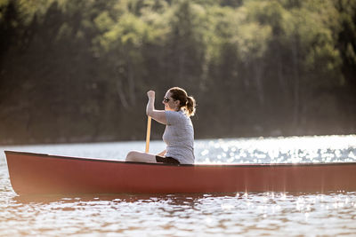 Woman in boat on lake against trees