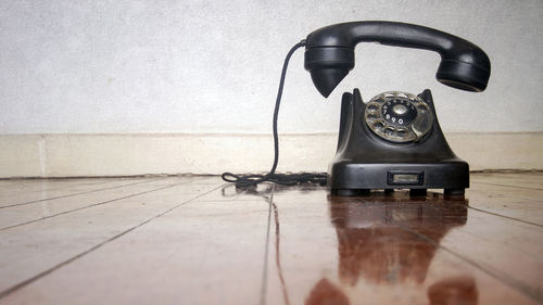 Close-up of telephone booth on table against wall