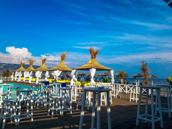 Chairs and tables on beach against blue sky