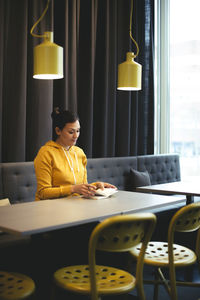 Mid adult businesswoman reading book in office cafeteria