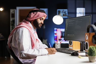 Side view of man using laptop at office