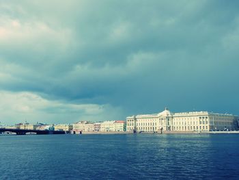 City at waterfront against cloudy sky