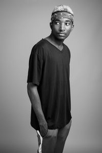 Portrait of young man standing against gray background