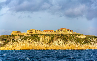 Built structure by sea against sky